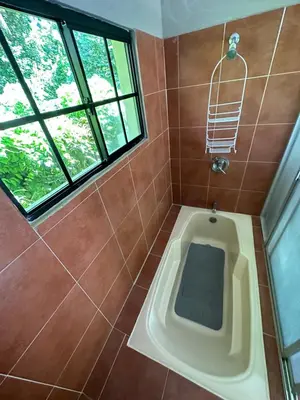 a bathroom with a tub with a window and a shower at Beach On The Rocks in El Zonte