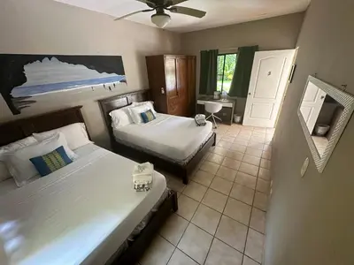 a hotel room with two beds and a bathroom at Beach On The Rocks in El Zonte