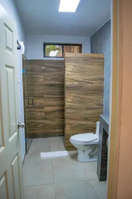 a bathroom with a toilet and a wooden shower stall at Tres Piedras in San Francisco Chinameca