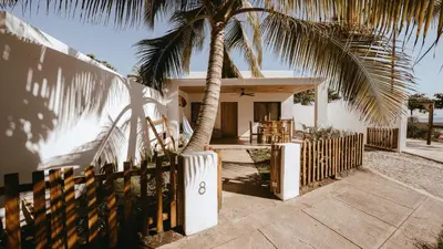 a house with a palm tree next to a fence at Coco Surf Tropical Village in La Libertad