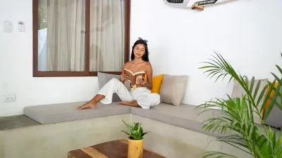 a woman sitting on a couch reading a book at Coco Surf Tropical Village in La Libertad