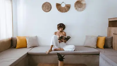 a woman sitting on a couch reading a book at Coco Surf Tropical Village in La Libertad