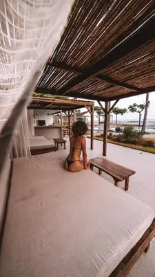 a woman sitting on a bed under a tent at Coco Surf Tropical Village in La Libertad