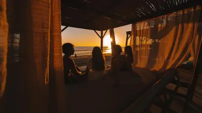 a group of people sitting on a porch watching the sunset at Coco Surf Tropical Village in La Libertad