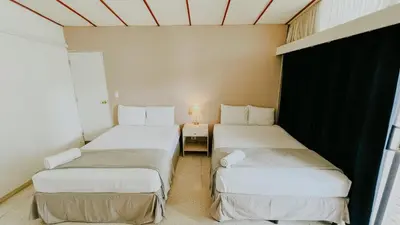 two beds in a small room with a table at LA RUTA HOTEL CORPORATIVO in San Salvador