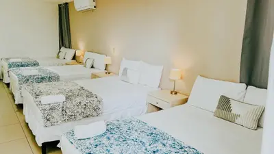 a room with three beds with white sheets at LA RUTA HOTEL CORPORATIVO in San Salvador