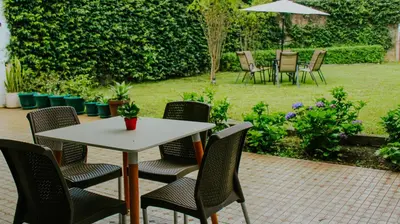 a table and chairs in a garden with an umbrella at LA RUTA HOTEL CORPORATIVO in San Salvador