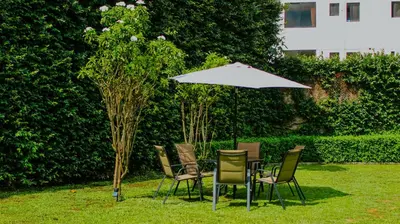 a table and chairs under an umbrella in the grass at LA RUTA HOTEL CORPORATIVO in San Salvador