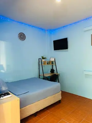 a bedroom with blue walls and a bed with a television at Hospedaje Mónaco in San Miguel