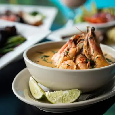 a bowl of soup with shrimp and limes on a plate at Mi Tierra Aeropuerto SAL Hotel y Restaurante in San Luis