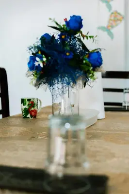 a glass vase filled with blue flowers on a table at Alojamientos Santa Marta La Unión in La Unión