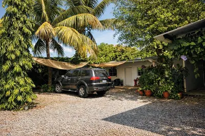 a car parked in front of a house with a palm tree at Habitación Deluxe Aire - Villa Valle Campo in Nahuizalco