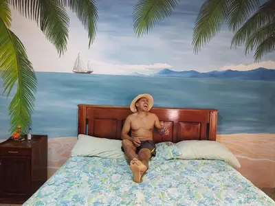 a man in a hat sitting on a bed at Casa Hotel Familiar in San Lucas