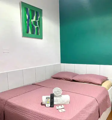 a bed with a pink blanket and two complimentary towels at hotel marsella in Sonsonate